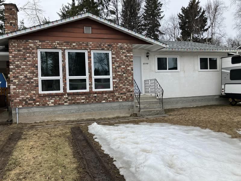 Black-frame windows on a brick-front bungalow in early spring