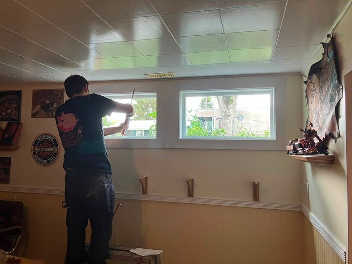 Installer fitting a new basement window from inside