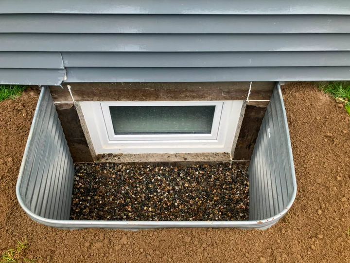 Galvanized window well around a new egress window on drainage rock