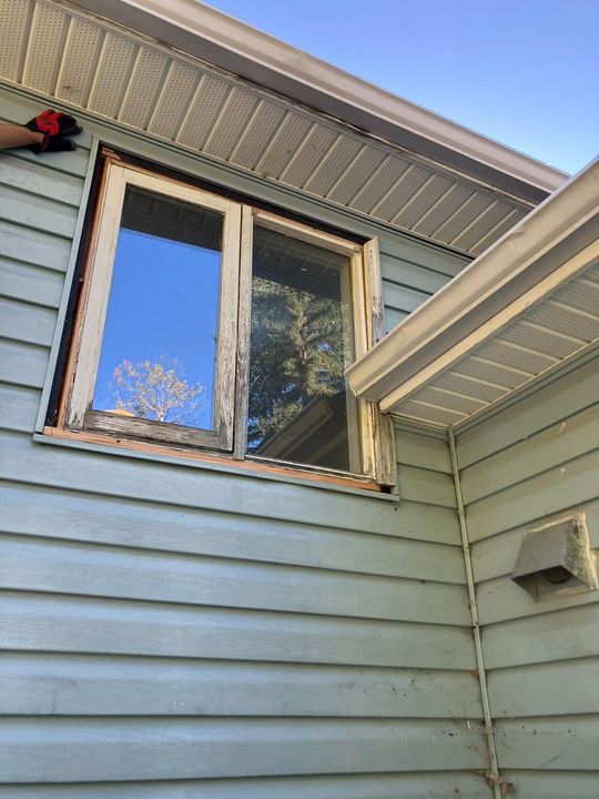 Old window on the light-blue siding before replacement
