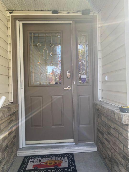 Before: Old brown entry door with sidelite inside a brick surround