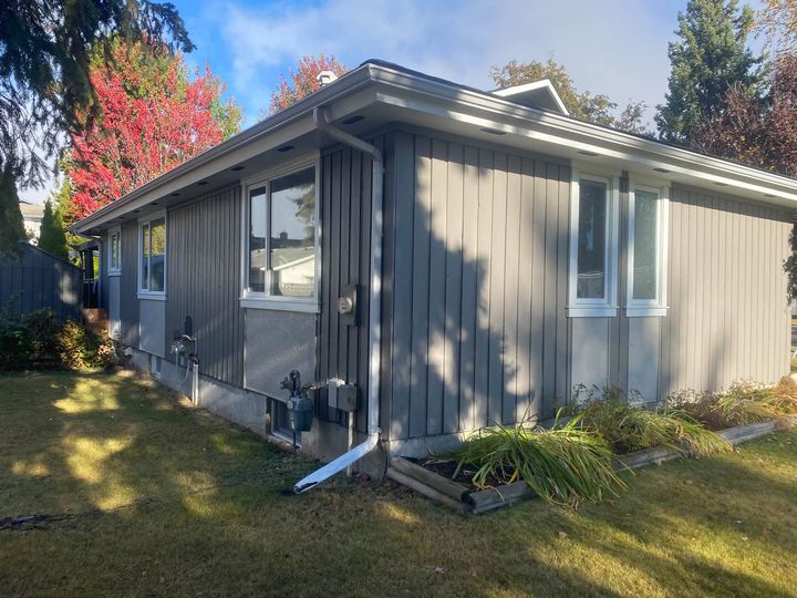 Grey bungalow with siding cut back around the window openings