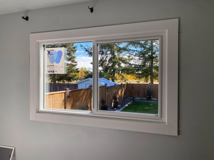 New sliding window with white trim in a grey-walled room