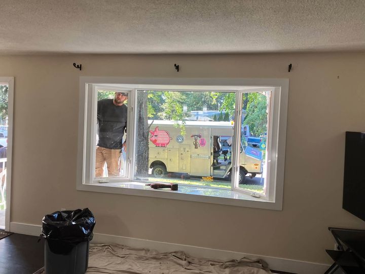Installer setting the new bay window from inside the living room