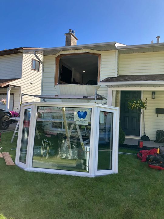 New triple-pane bay window staged on the lawn of a yellow two-storey home